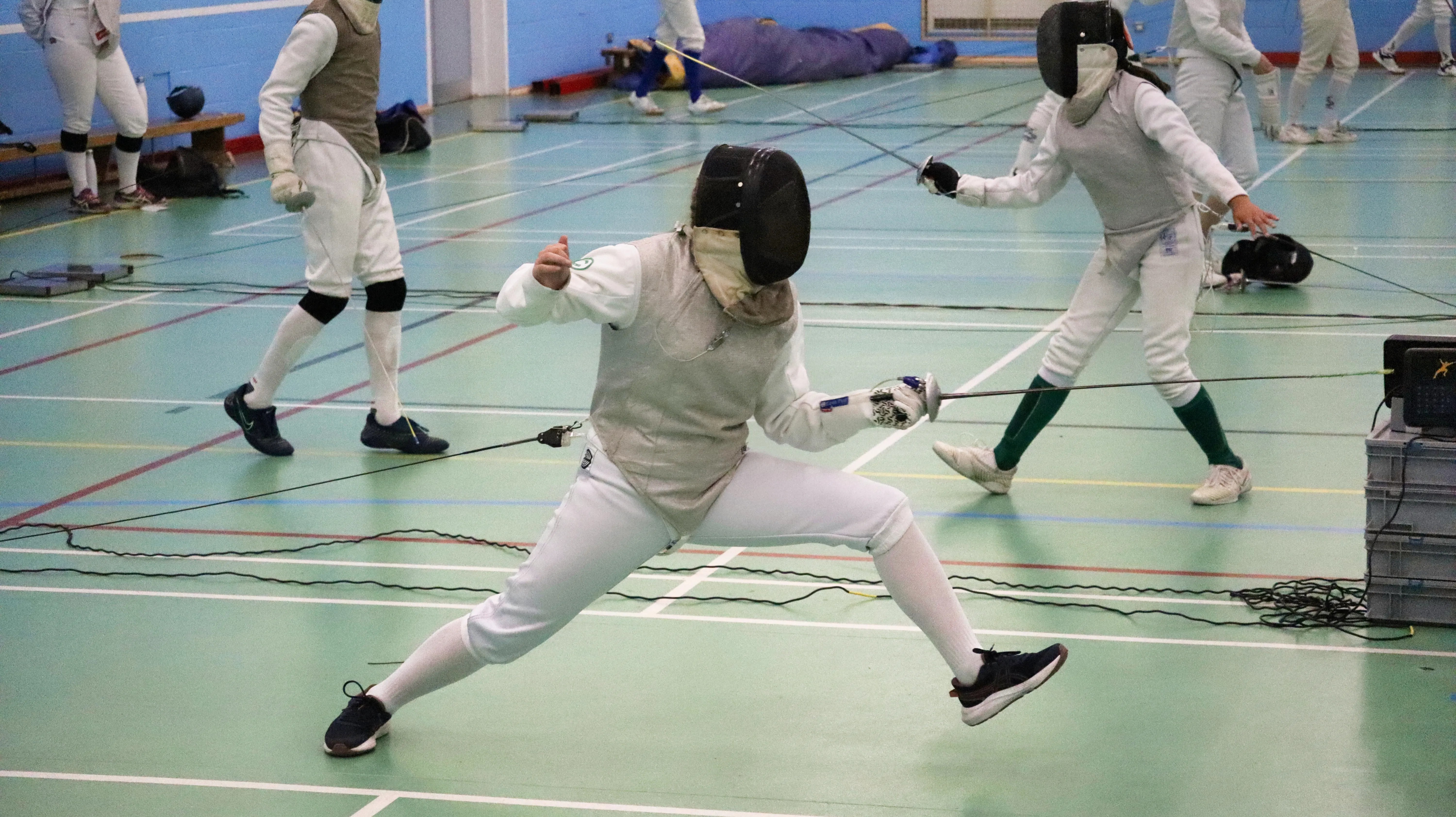 A younger foil fencer mid-lunge.